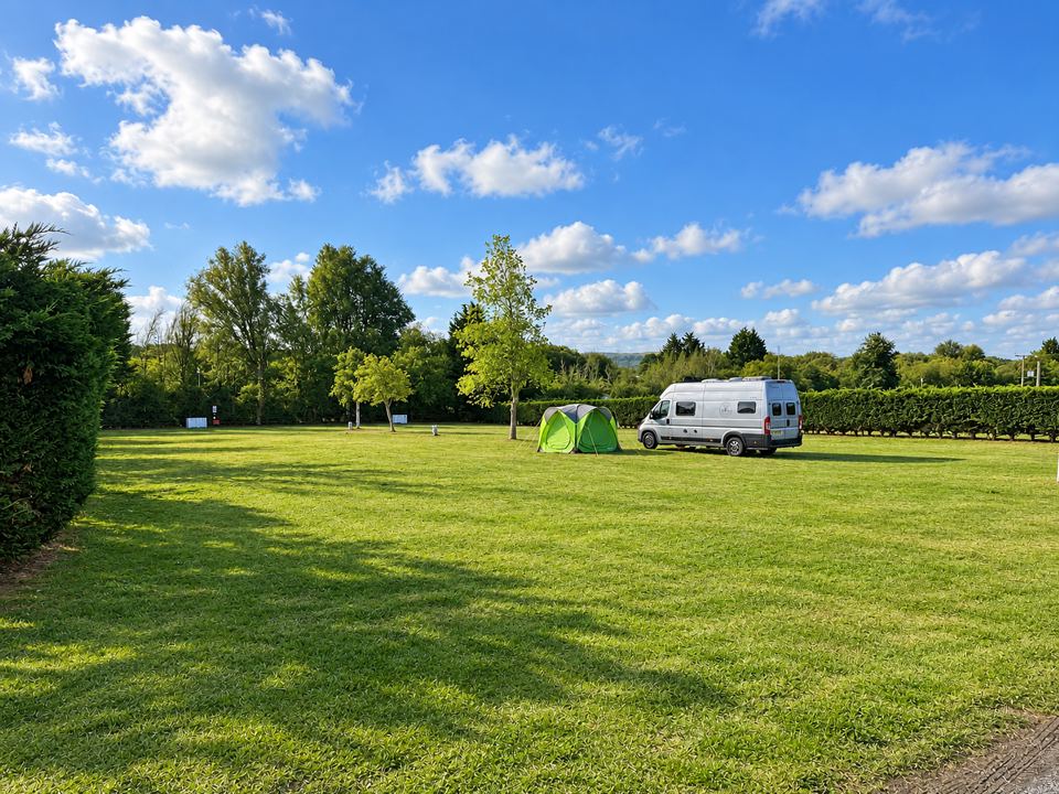 Grass field with tent and motorhome