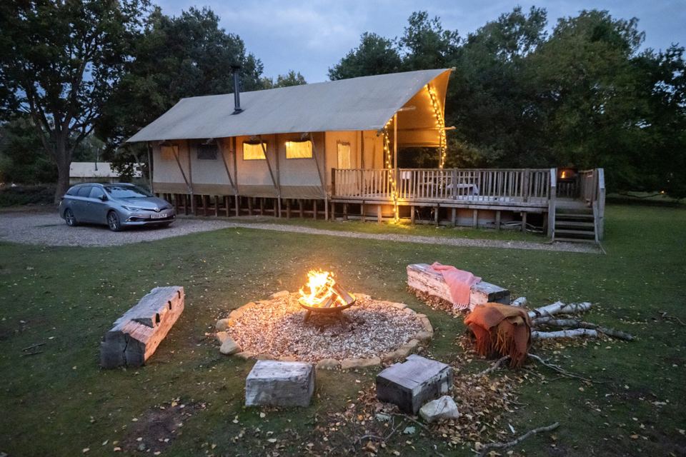Safari tent and fire pit at dusk