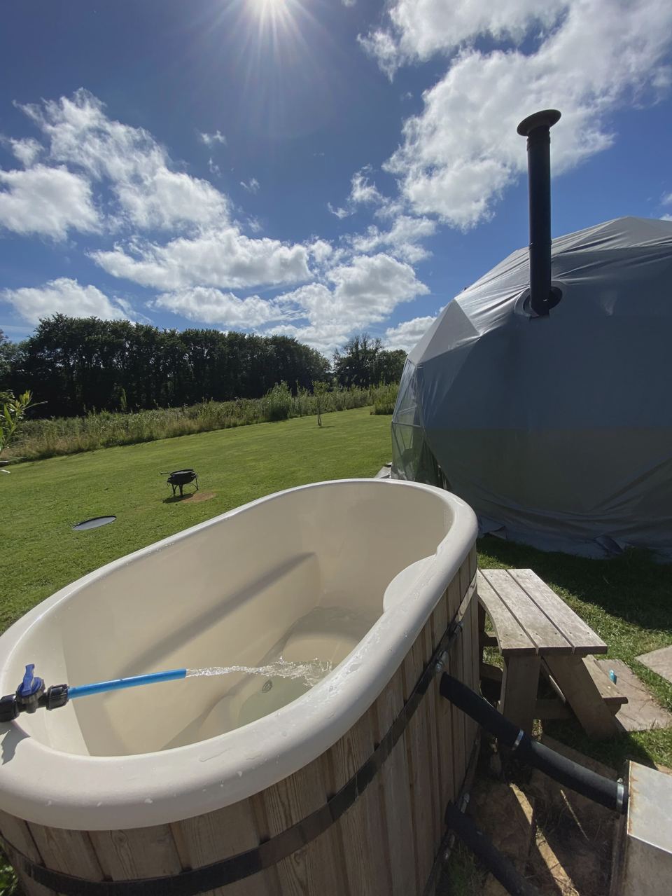 Wood-fired hot tub beside a dome