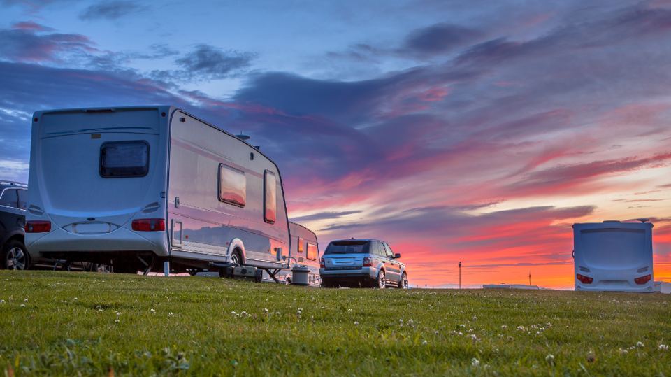 Caravan on a field at sunset