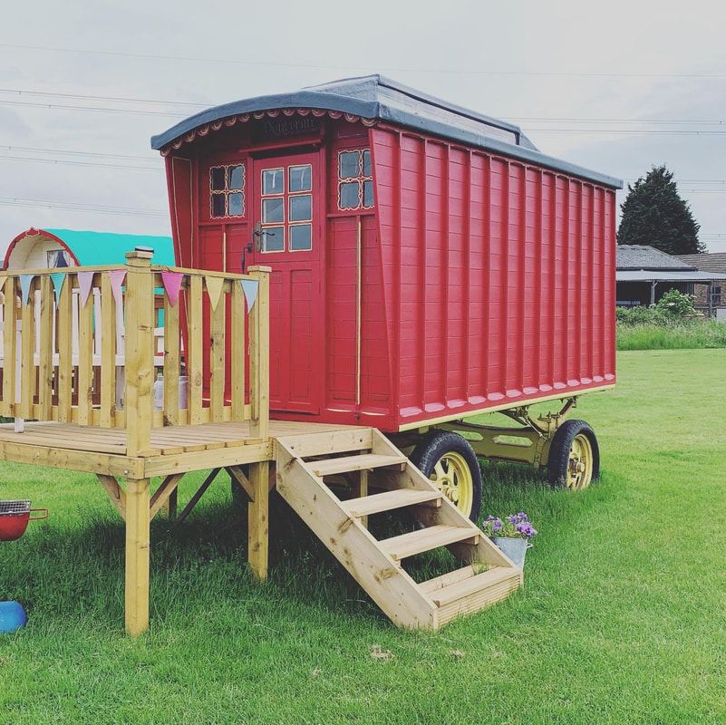 Red glamping wagon on decking