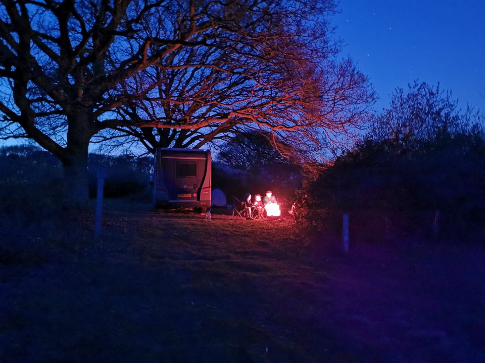 Campfire by a van at dusk