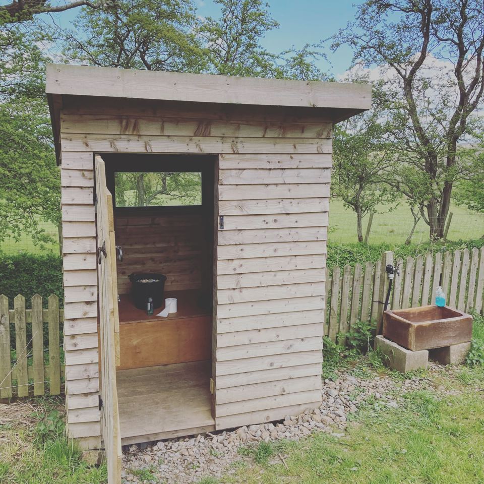 Wooden toilet cabin by the fence