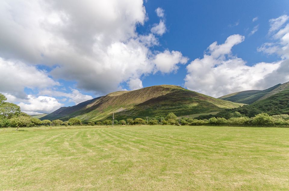 Open grass field below the hills