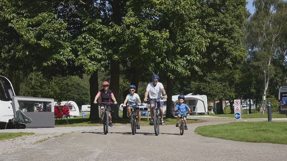 Family cycling past the pitches