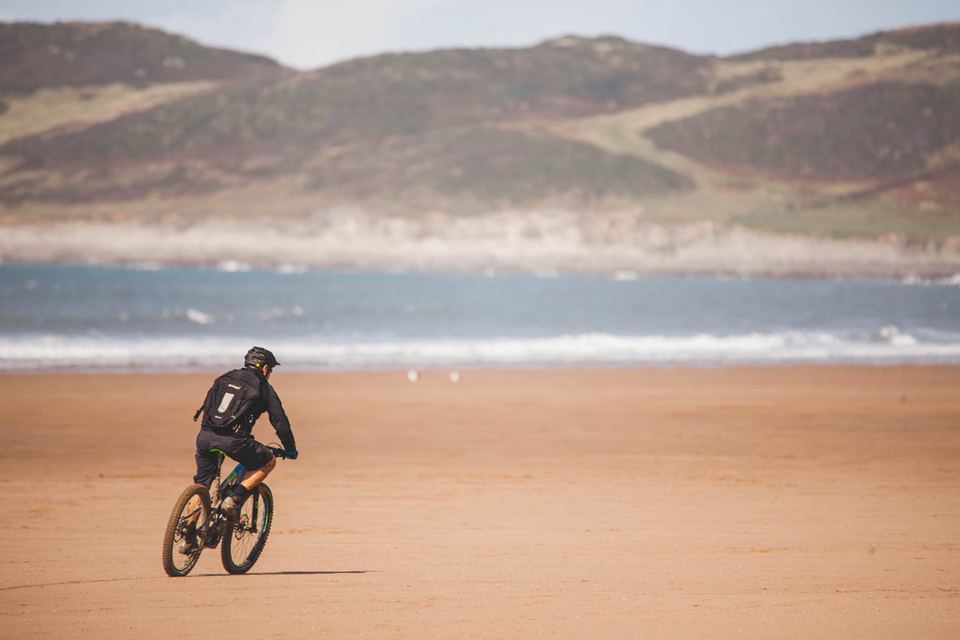Cyclist on the sand by the surf
