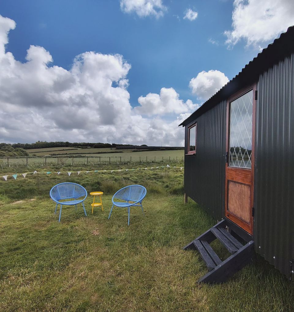 Shepherd's hut with chairs on grass