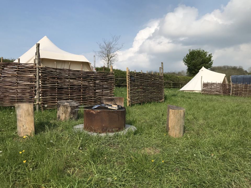 Fire pit and bell tents behind windbreaks