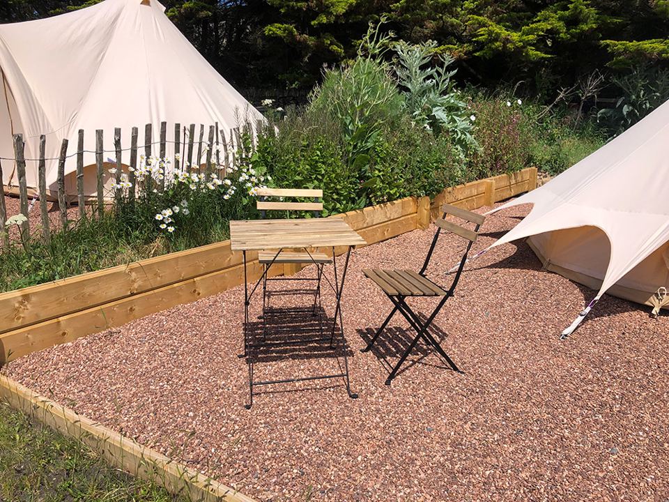 Bell tents on gravel beside the garden