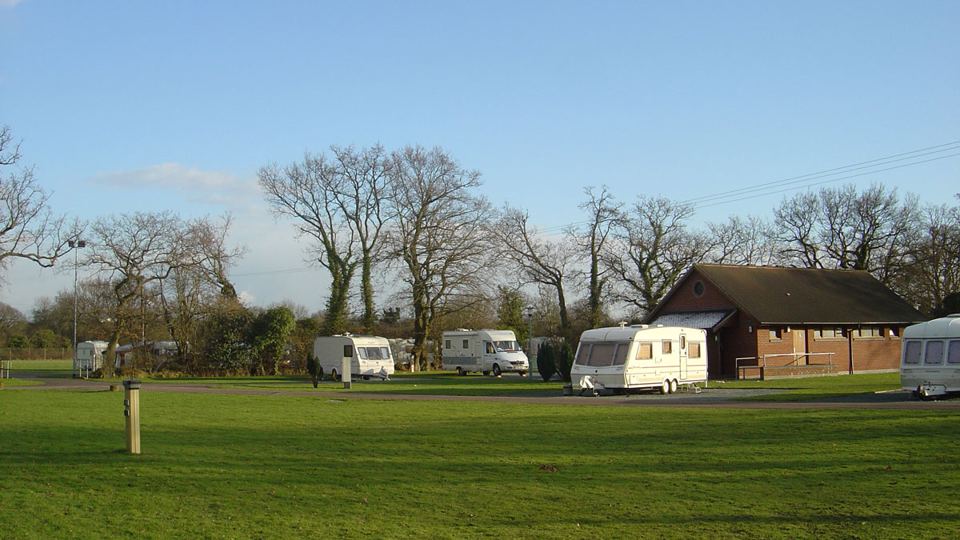 Caravans on tree-lined grass