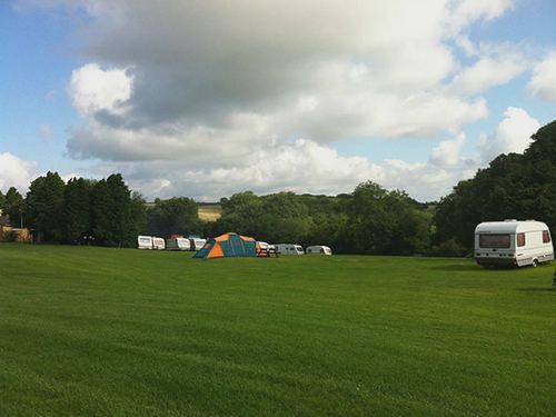 Open grass field with tent and tourer