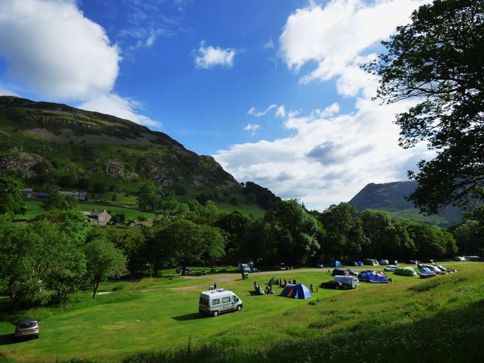 Tents and campervan in the field below fells