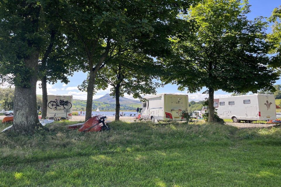 Motorhomes under trees by the lake