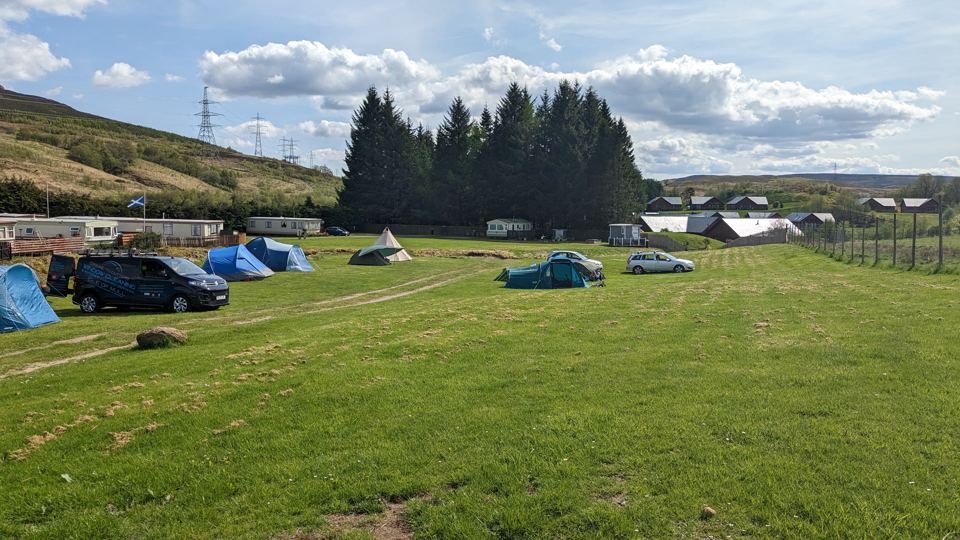 Tent field with trees beyond