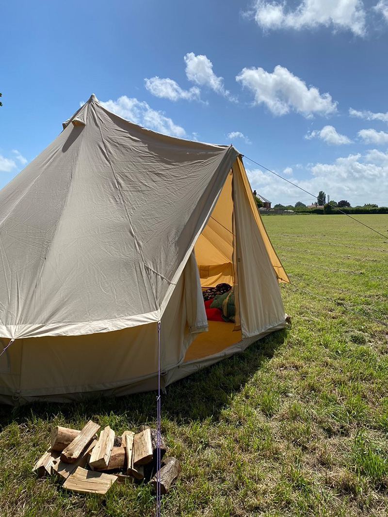 Bell tent and logs on the field