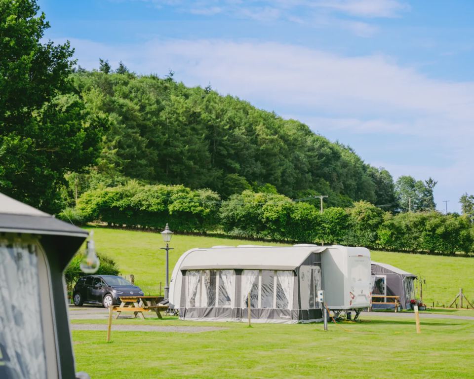 Caravan and awning below the woods