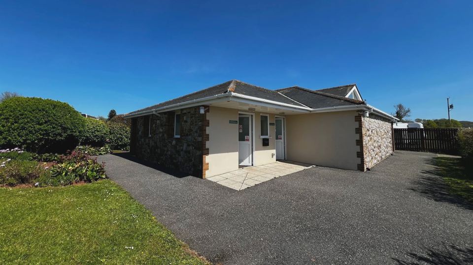 Single-storey lodge with gravel drive