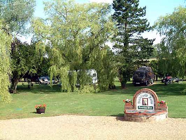 Entrance sign and pitches among trees