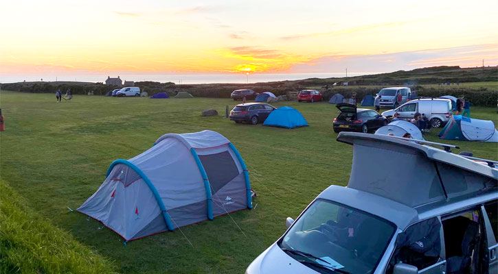 Tent and camper on the grass at sunset