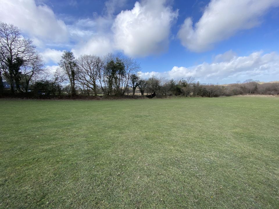 Level field with hedgerow beyond