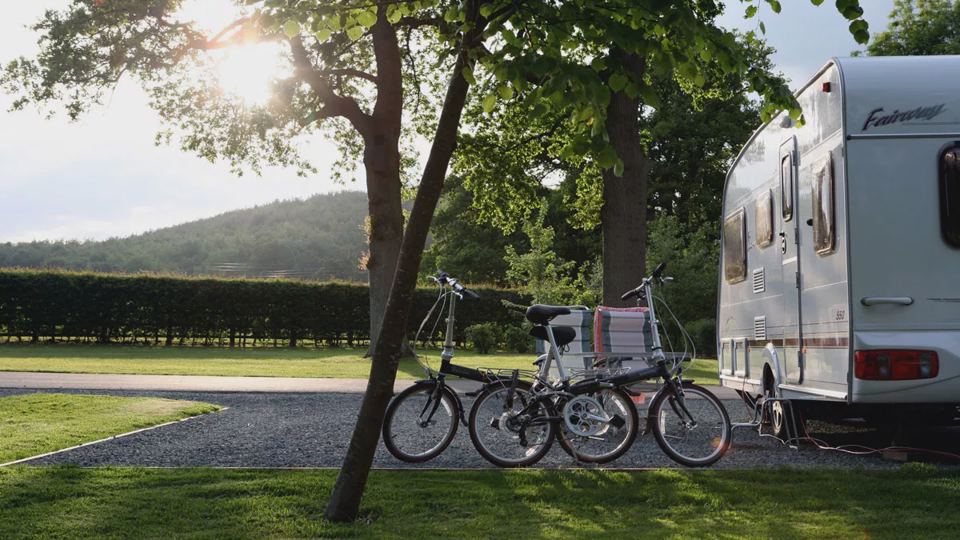 Caravan and bikes under trees