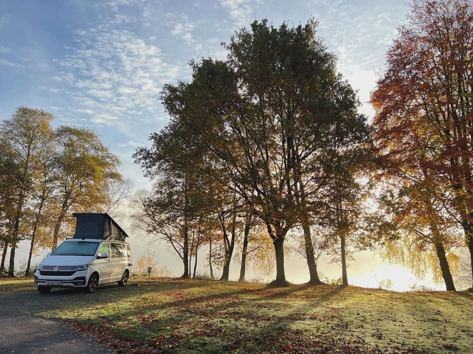 Campervan under trees by the loch