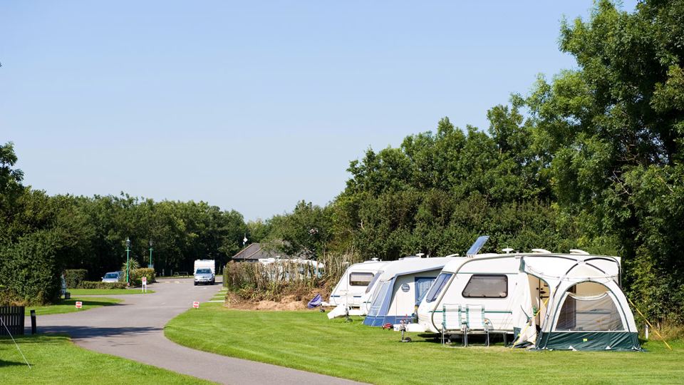 Caravan with awning among trees