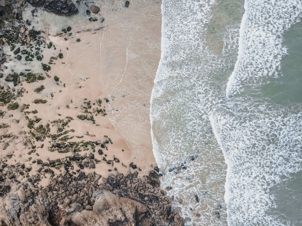 Waves on rocks above a sandy beach