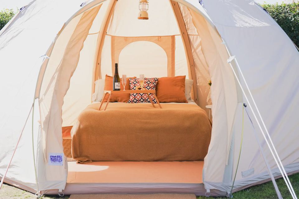 Inside a bell tent with orange bedding