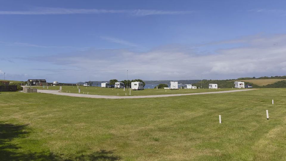 Grass pitches with caravans in distance