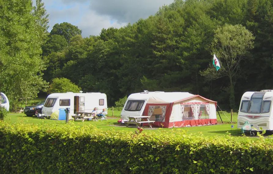 Tourers pitched below wooded hills