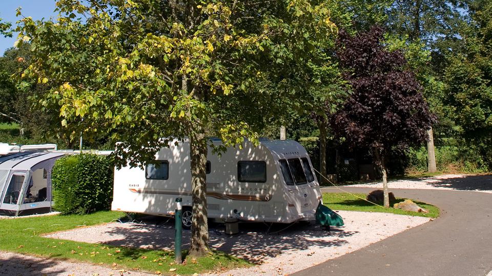 Caravan on the gravel pitch under a tree