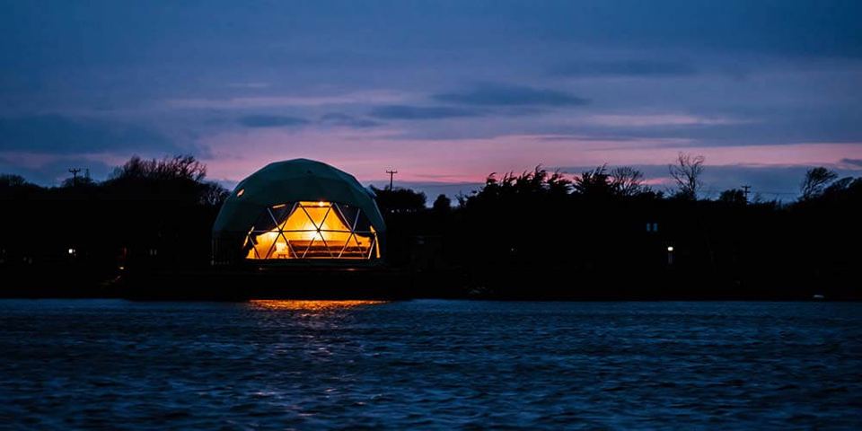 Geodesic dome lit up over the lake