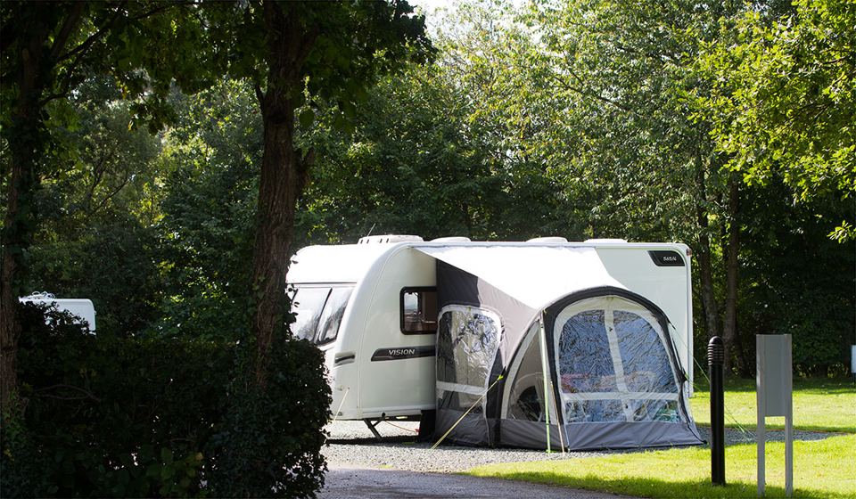 Caravan with awning under trees