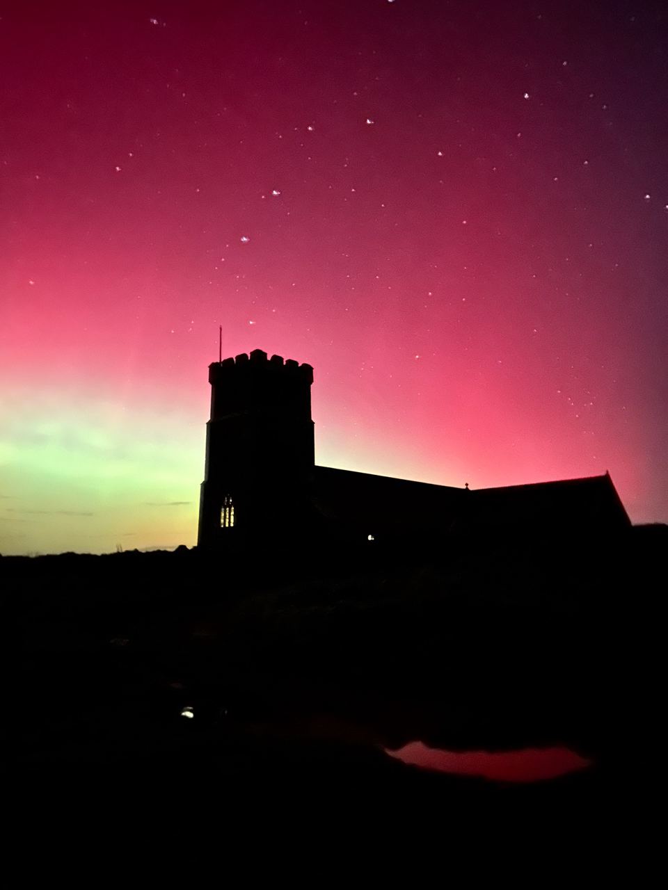 Church silhouette under aurora