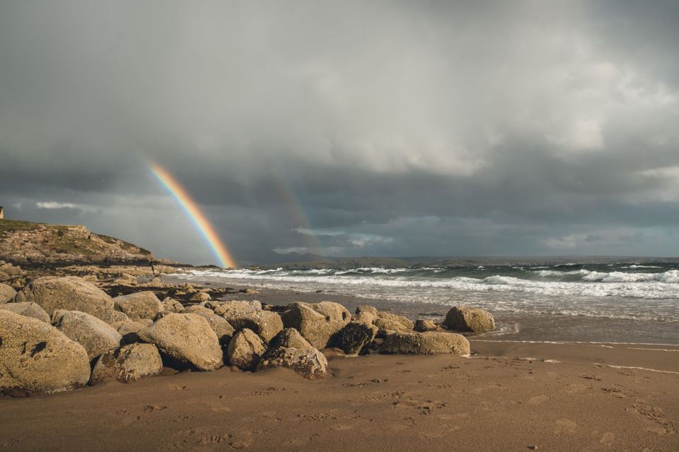Rocky beach under a rainbow