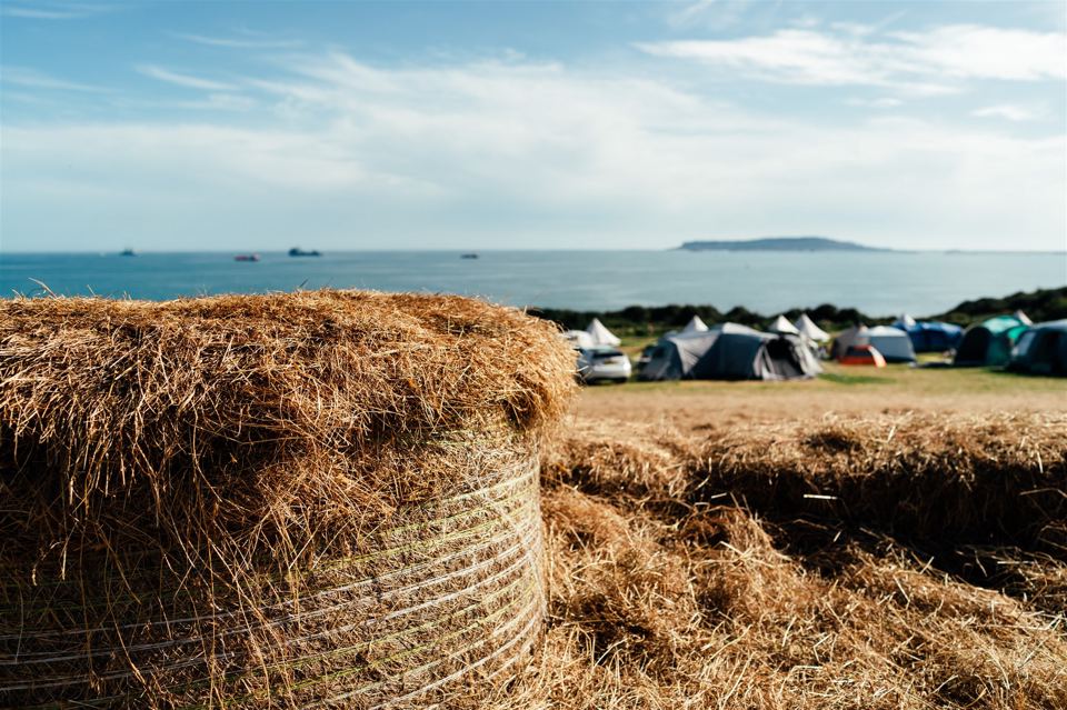 Tents by the sea behind a hay bale
