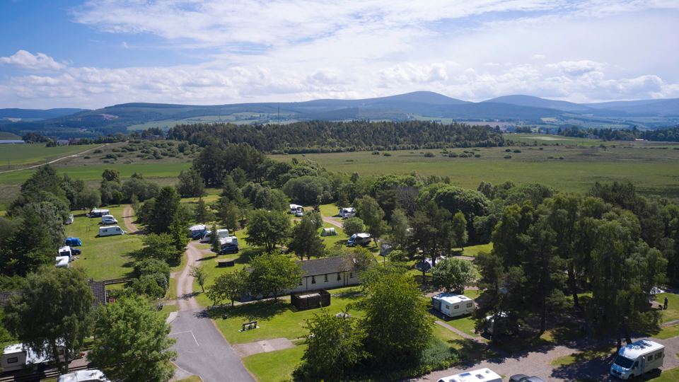 Site among trees, hills beyond