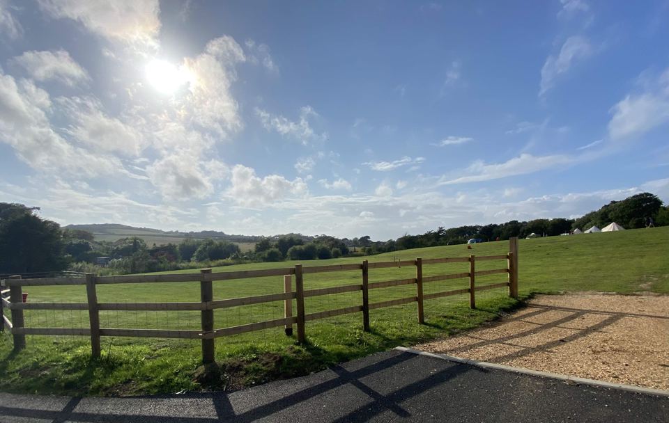 Fenced field with bell tents beyond