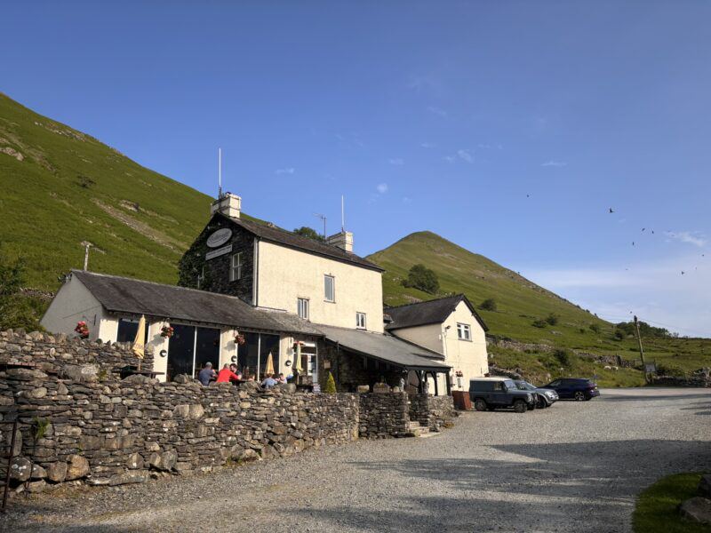 Inn with parked cars below the fells