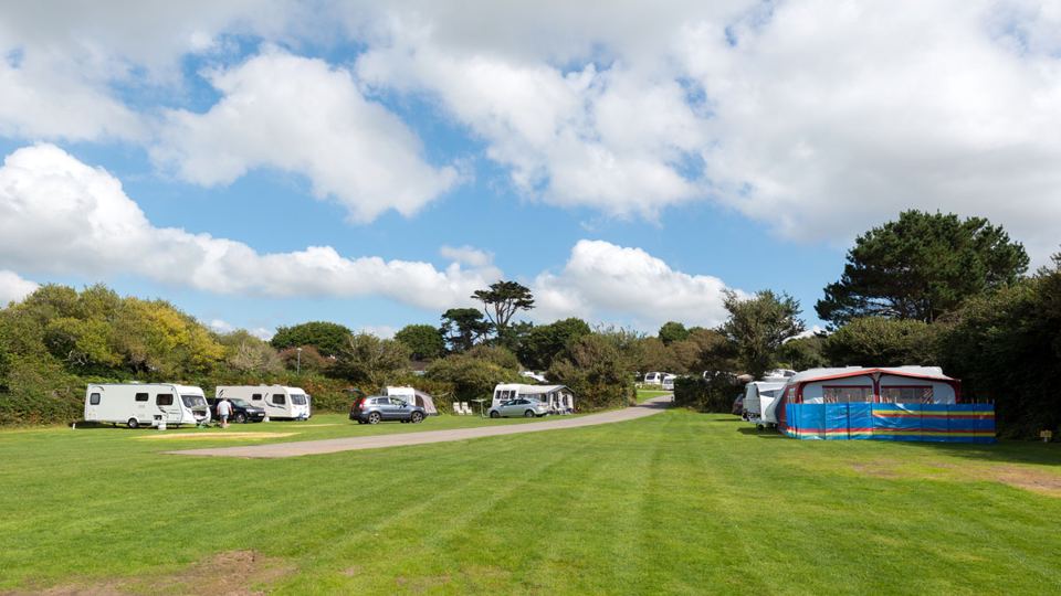 Caravans on the grass beneath trees
