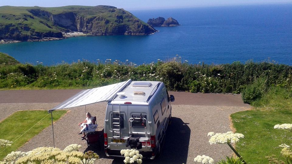 Campervan under an awning by the cove