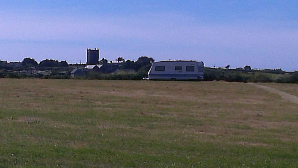 Caravan in the field with church beyond