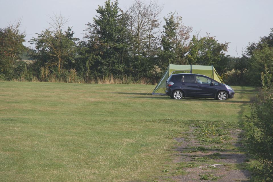 Car and tent on open grass